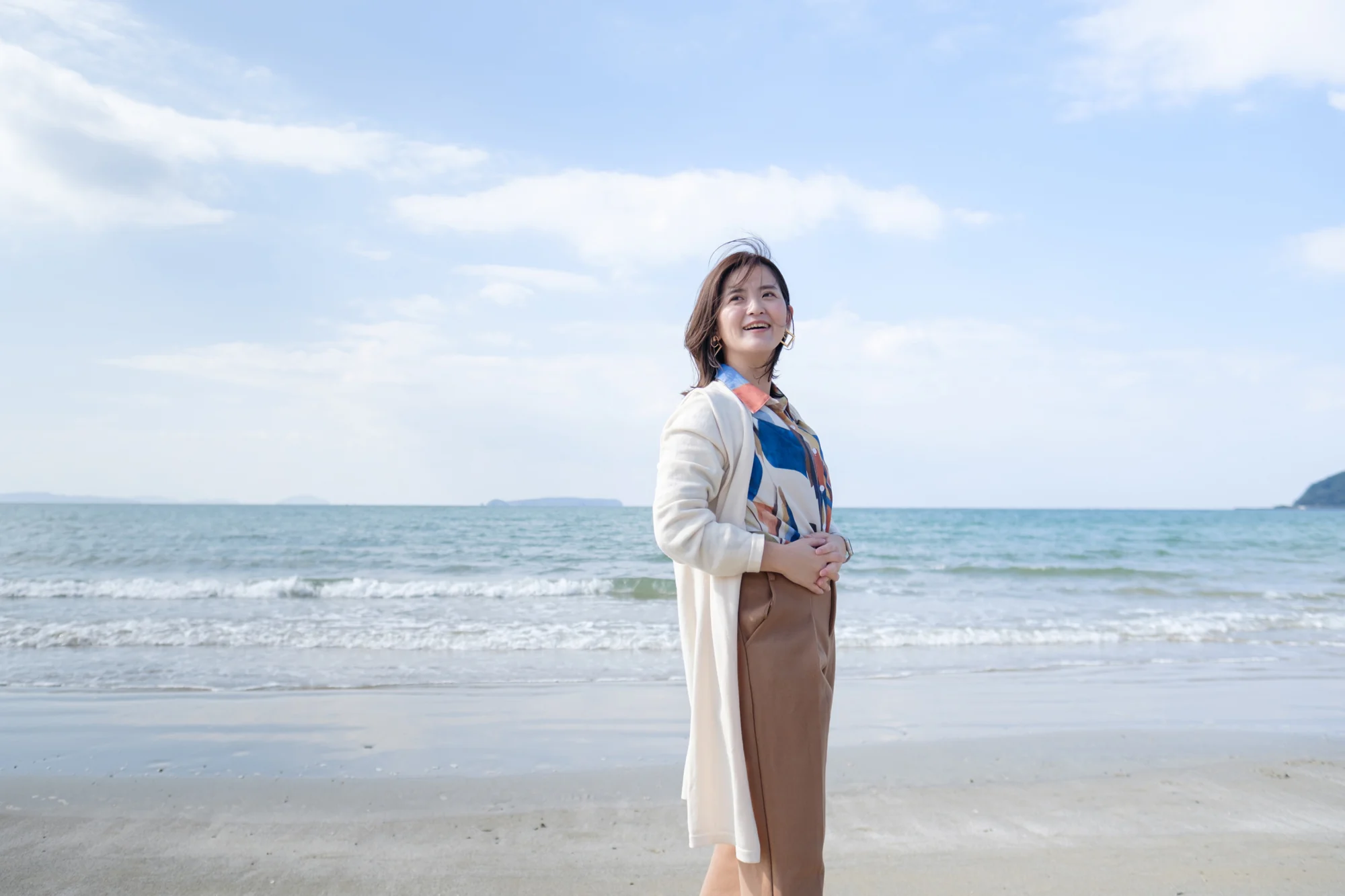海を背景に、笑顔で前を向く英語コーチ伴さおり